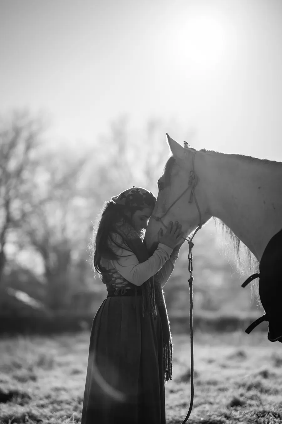 Jeune femme câlinant un cheval blanc, front contre front, photo en noir et blanc