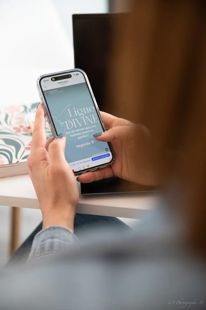 Mains tenant un smartphone affichant une publicité Instagram pour 'Ligne Divine', une gamme de soins féminins