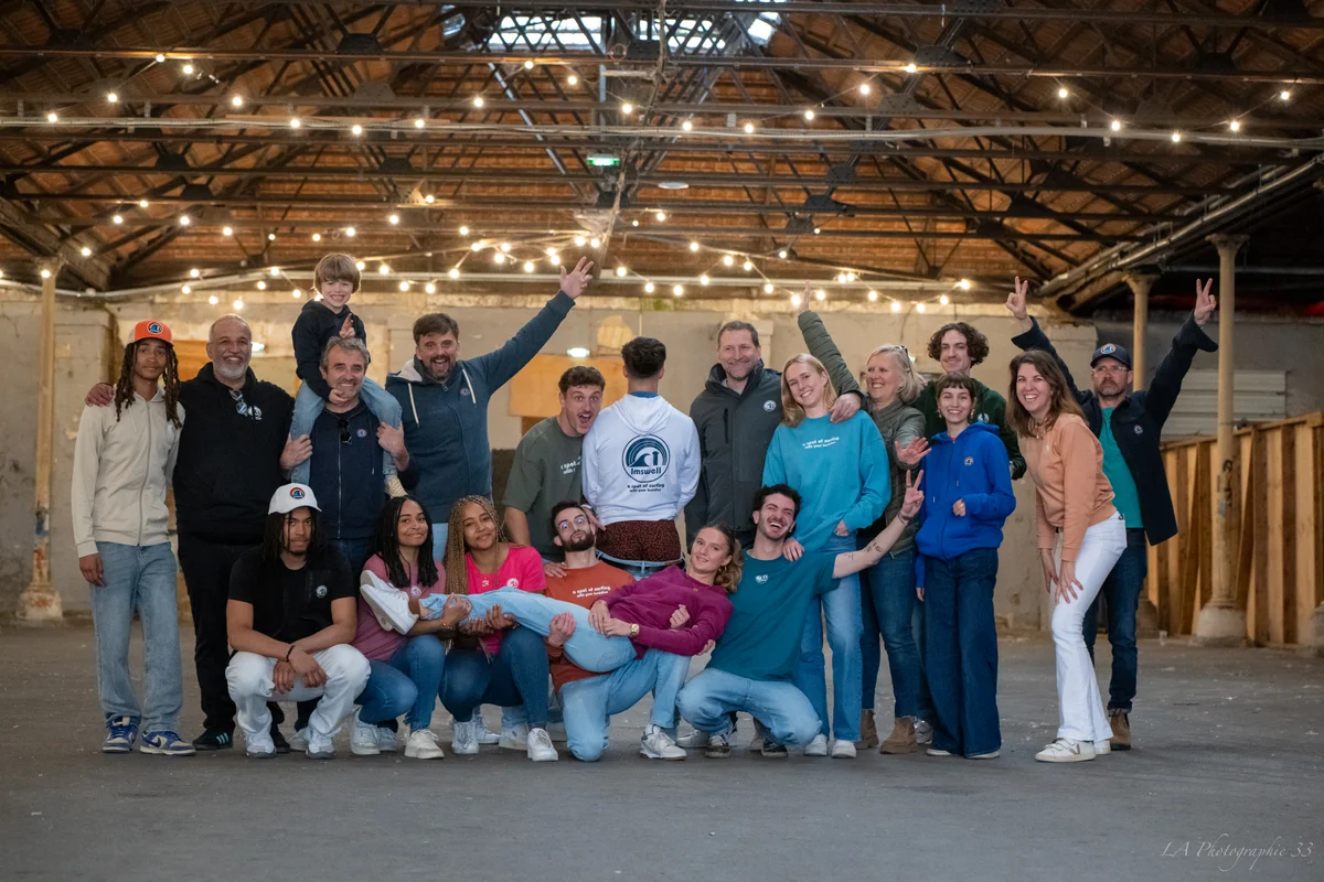 Photo de groupe joyeuse d'une équipe d'entreprise dans un entrepôt illuminé de guirlandes