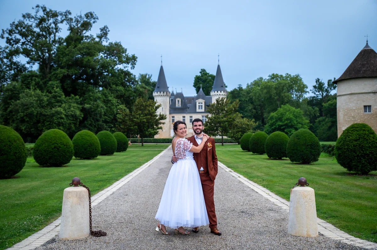 Mariés enlacés sur une allée gravillonnée menant à un château à tourelles