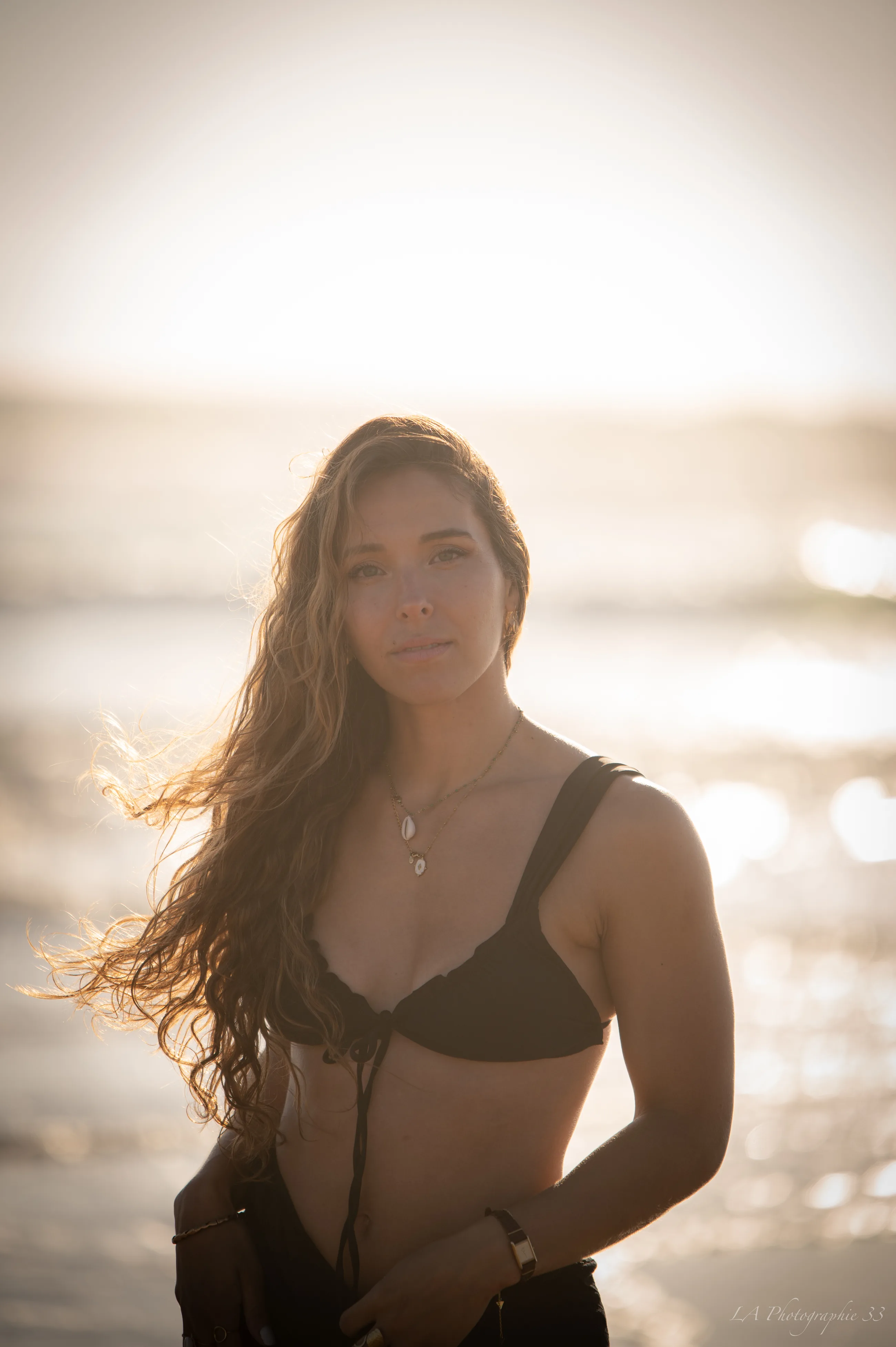 Portrait d'une jeune femme à contre-jour sur la plage au coucher du soleil
